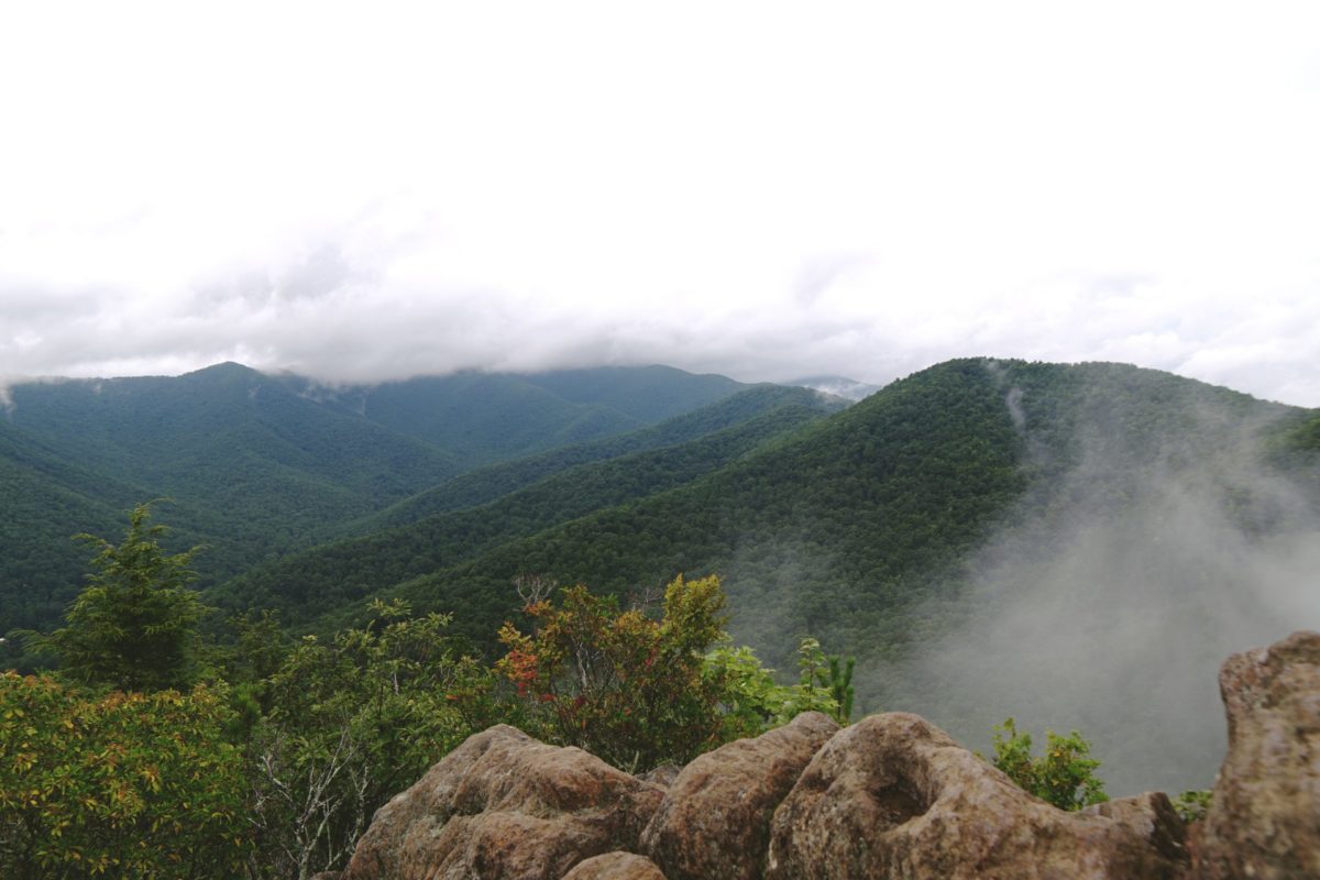 Rocks in the foreground of a overlook of mountains shrouded by fog.