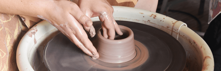 Hands sculpting thrown clay.