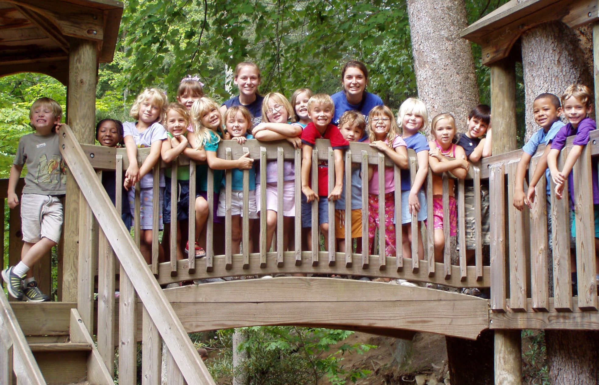 Children smiling on the bridge of the Robert Lake Park playground.