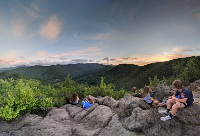 Group of hikers on top of mountain during sunset.