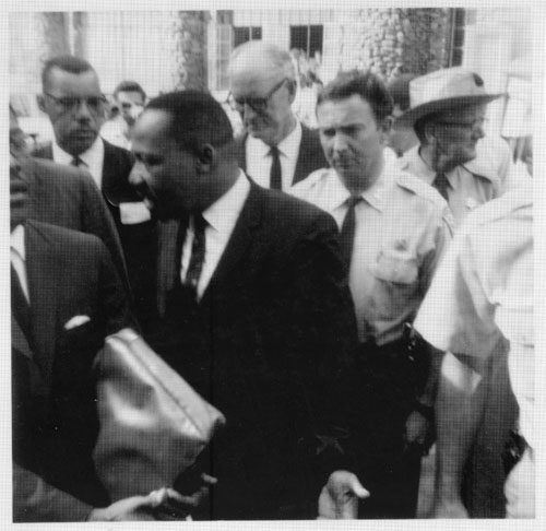 Martin Luther King Jr. exiting Anderson Auditorium with security detail.